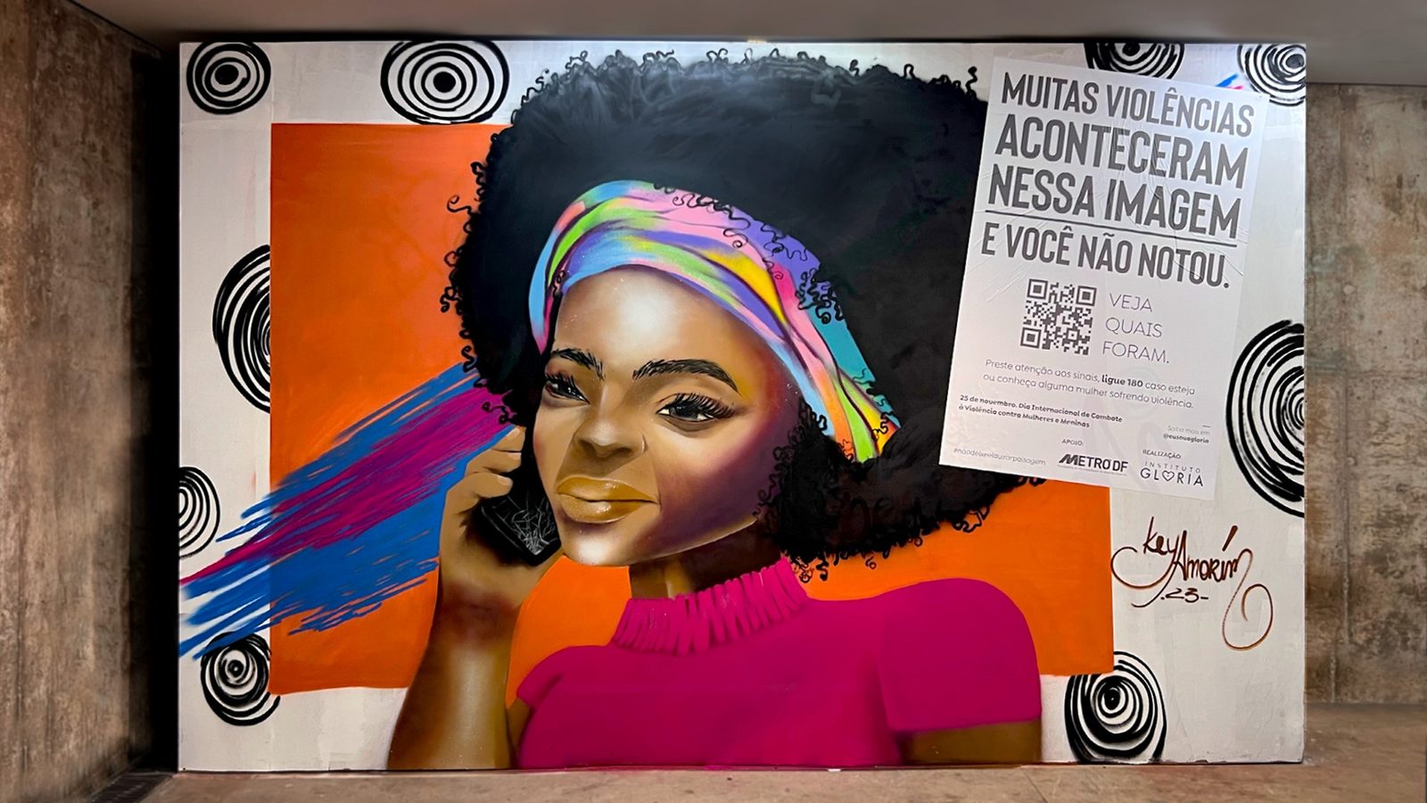 Mural de Key Amorim (estação Praça do Relógio) no estado final: a mulher ao telefone, semblante sério, com o cartaz 'Muitas violências aconteceram nessa imagem e você não notou. Veja quais foram.' e o QR Code